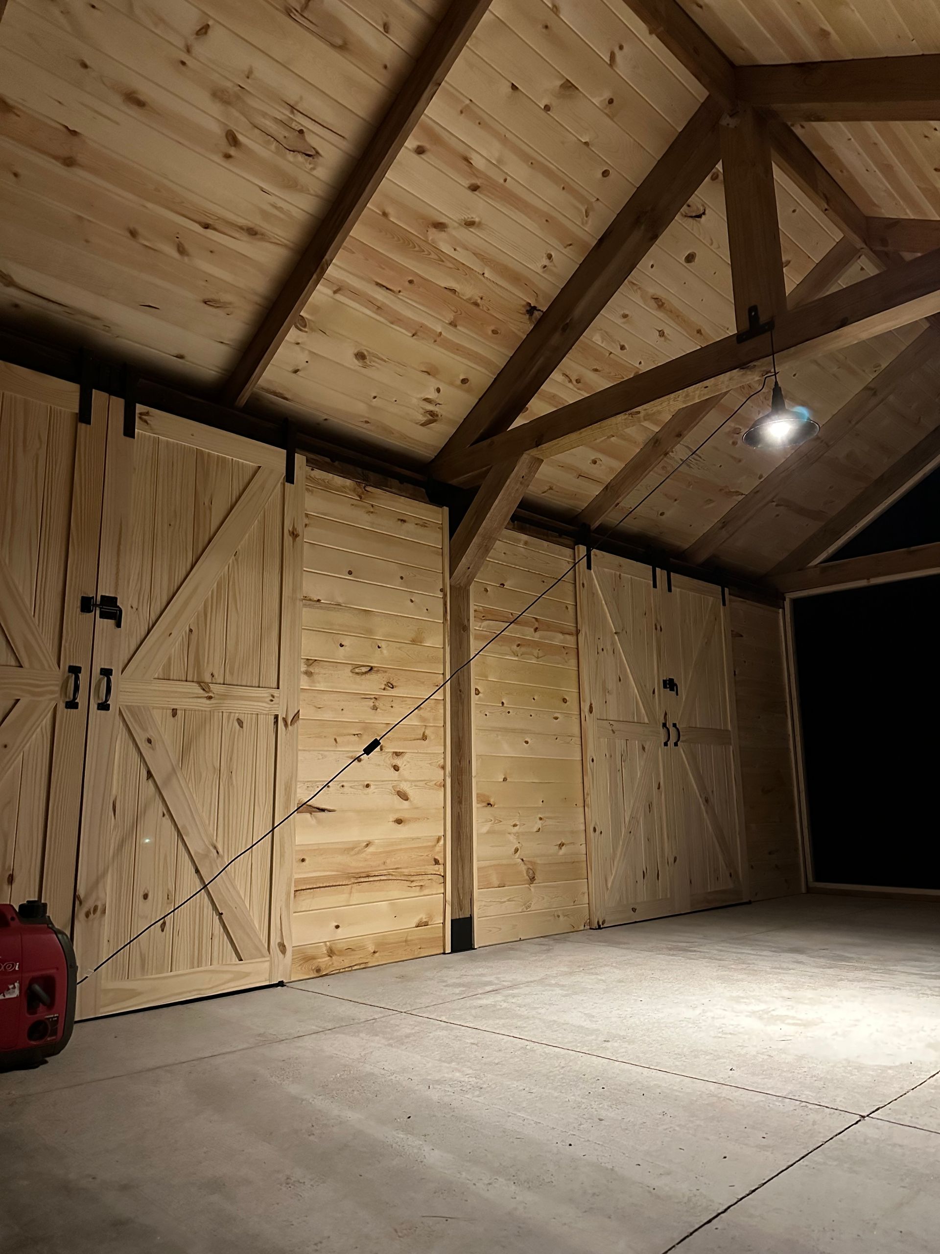 An empty garage with wooden doors and a light on the ceiling.