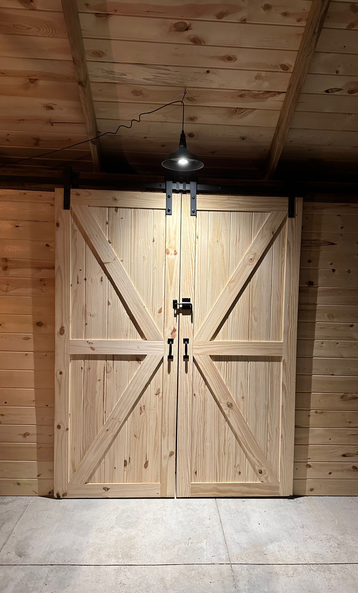 A pair of wooden sliding barn doors in a wooden building.