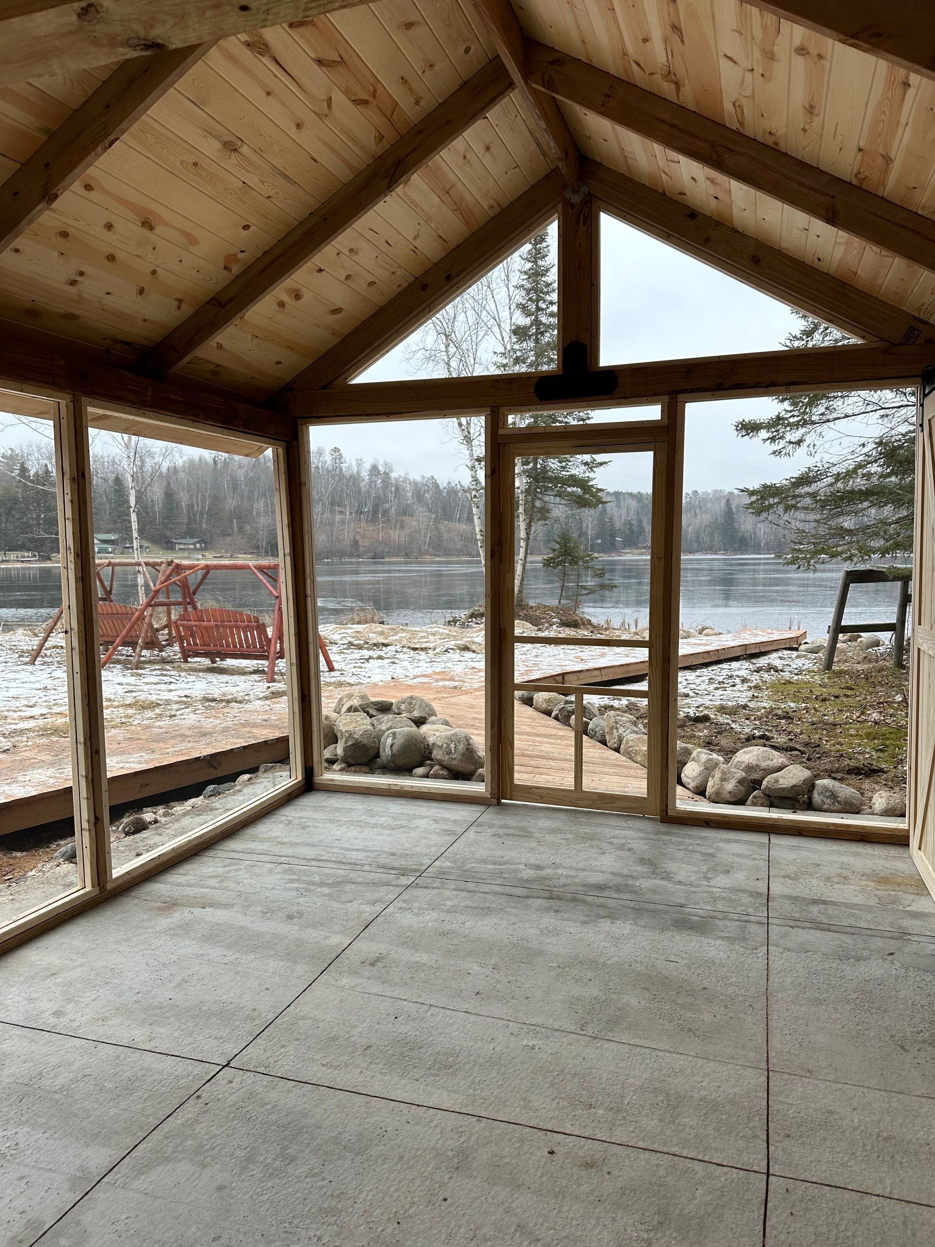 A room with a lot of windows and a view of a lake.