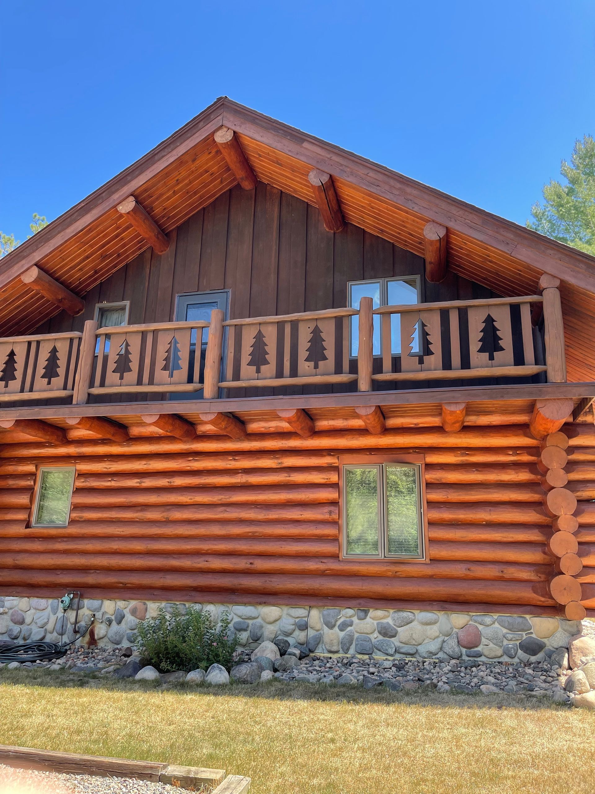 A log cabin with a balcony and trees on the roof