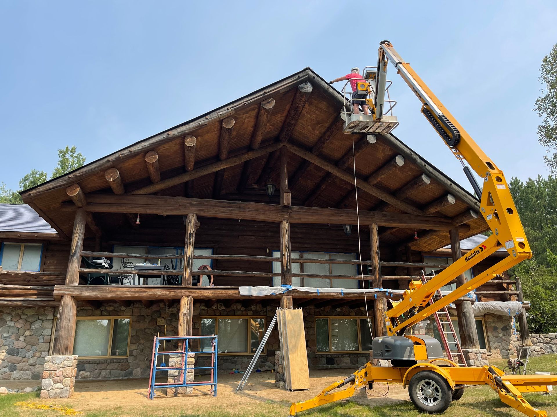 A man is working on the roof of a large log cabin.