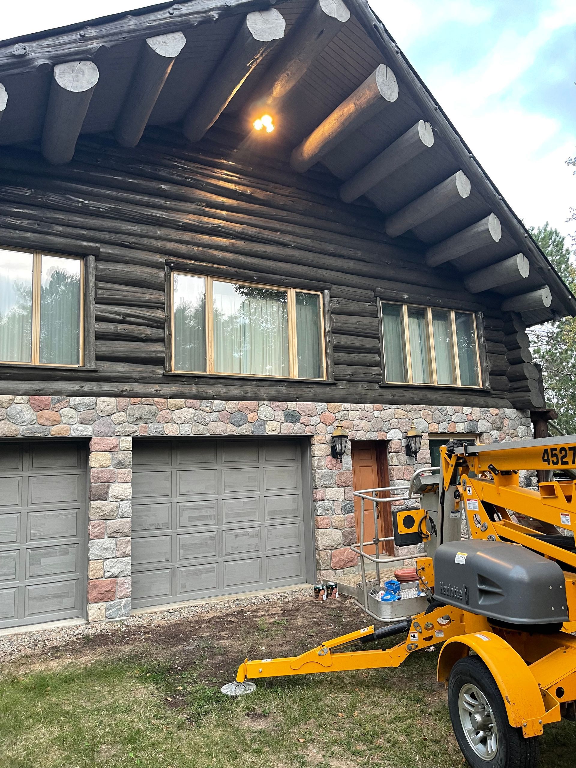 A yellow trailer is parked in front of a log cabin.