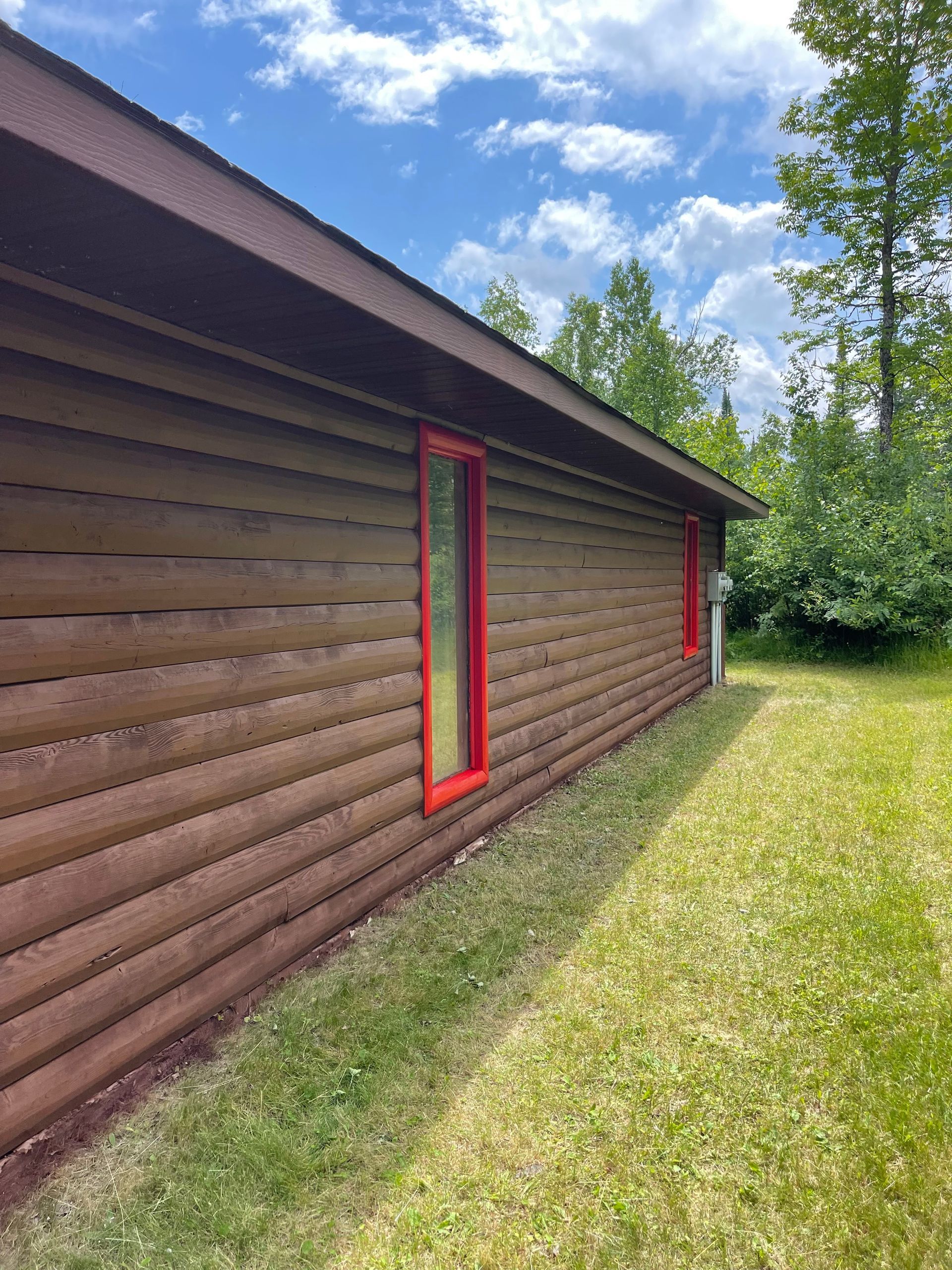 A log cabin with a red window on the side of it.