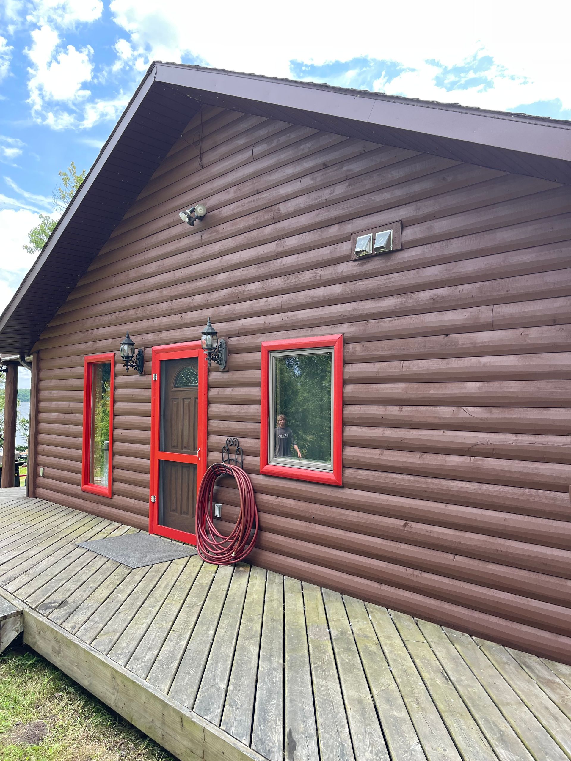 A log cabin with a wooden deck and a wreath on the door.