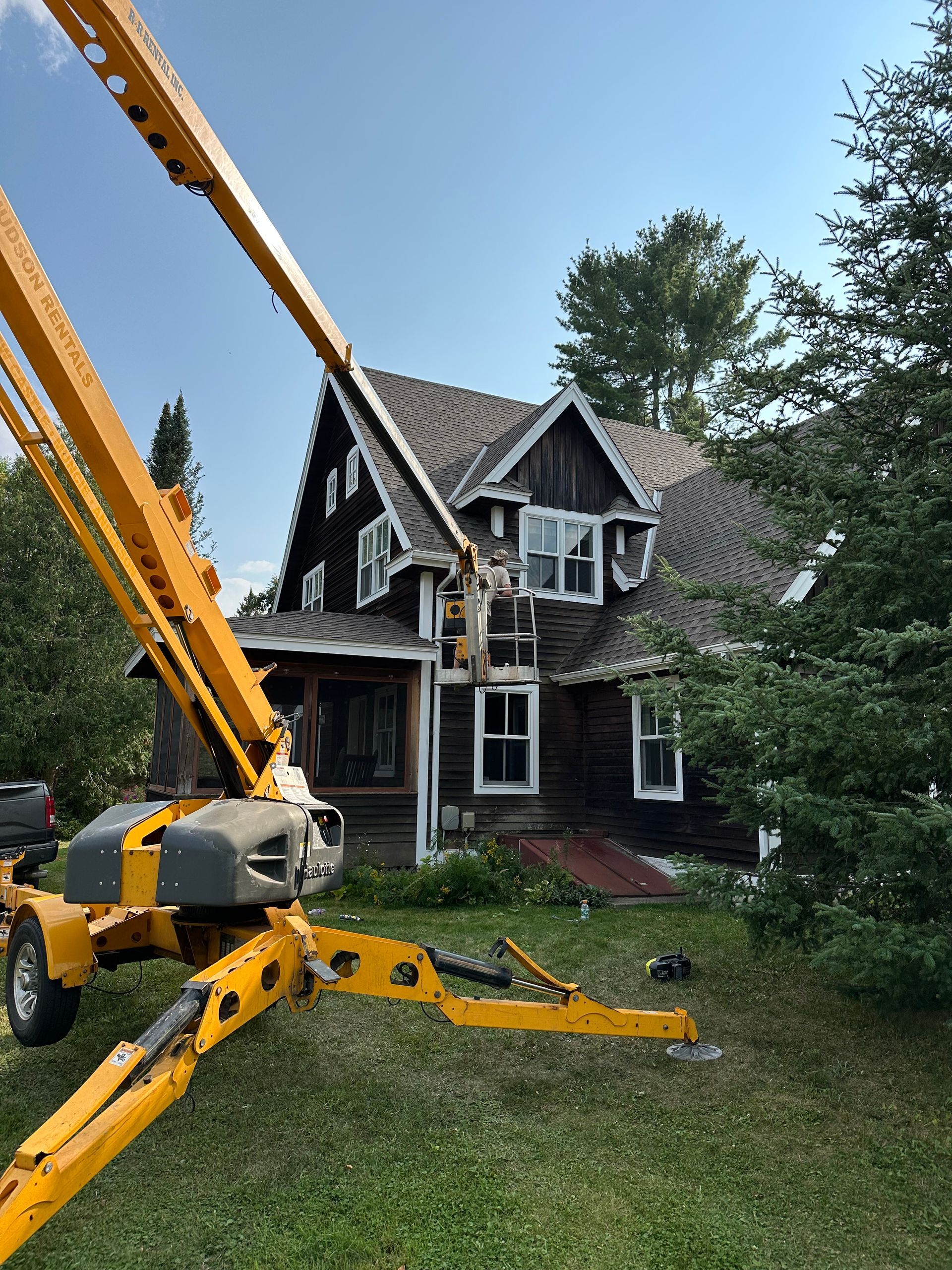 A yellow crane is sitting in front of a house.