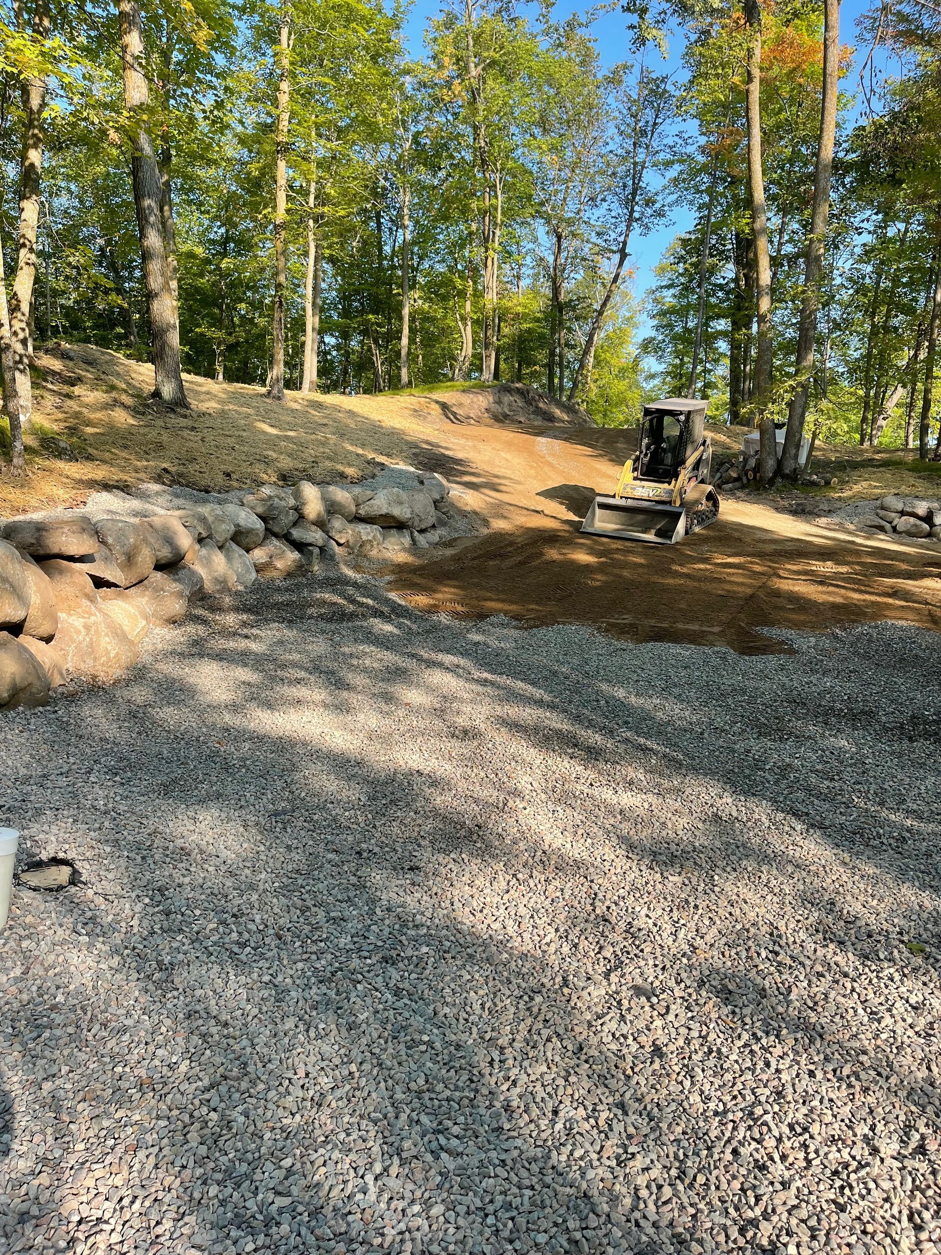 A tractor is driving down a gravel road in the woods.