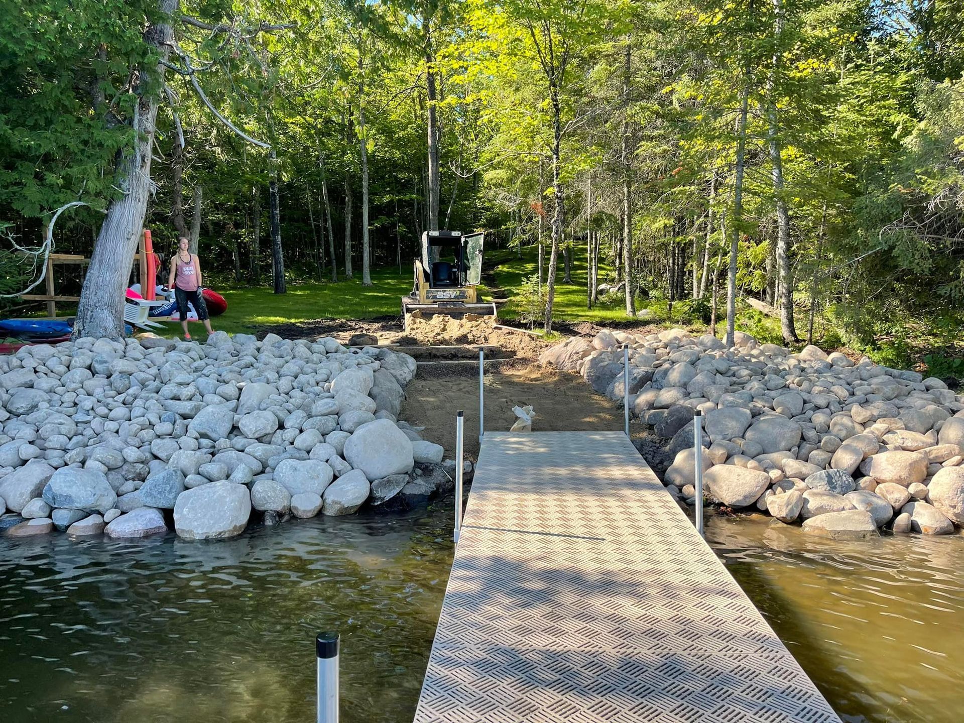 A dock is surrounded by rocks and trees next to a body of water.
