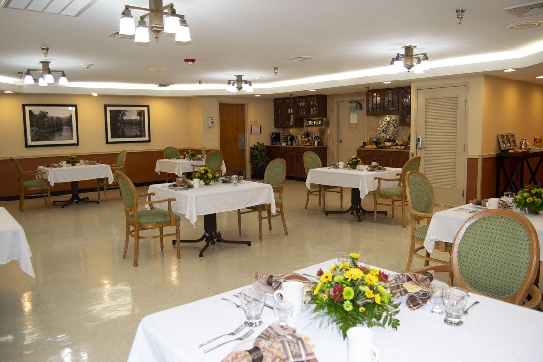 A large dining room with tables and chairs and flowers on the tables