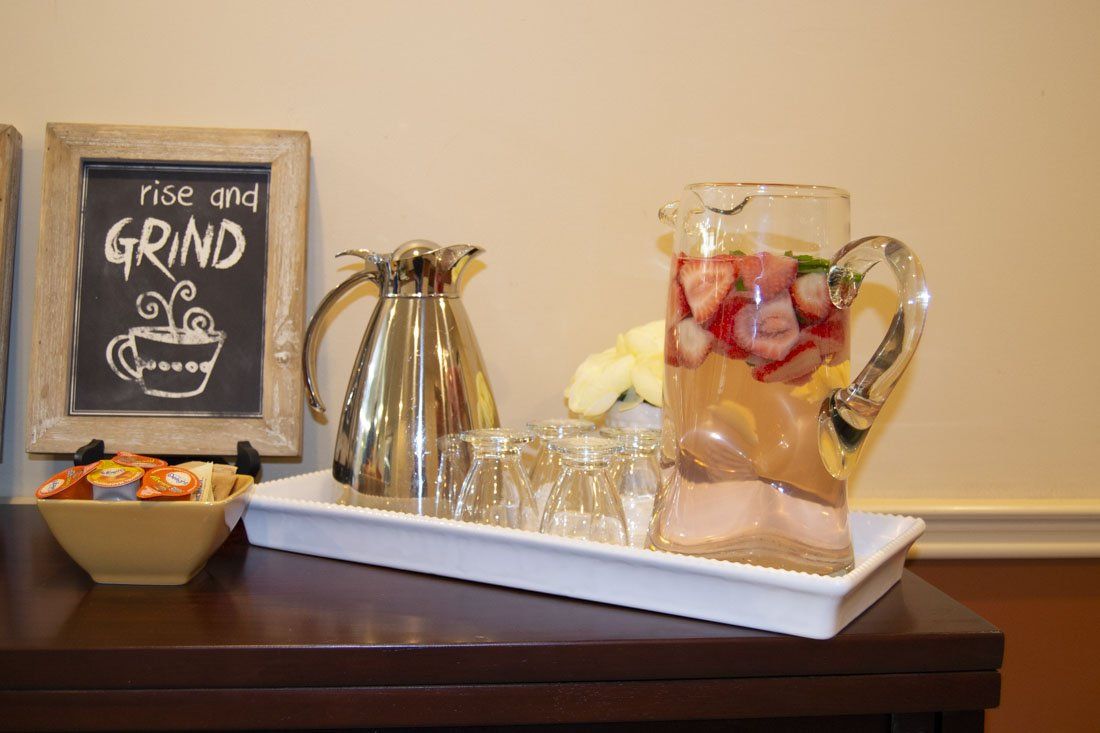 A pitcher of water with strawberries in it is on a tray on a table.