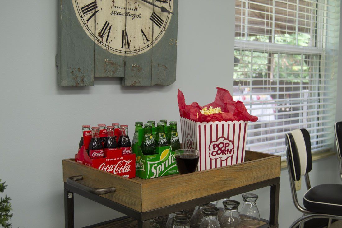 A wooden cart with bottles of soda and popcorn on it