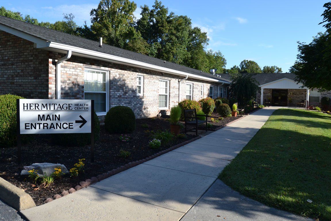 A brick building with a sign pointing to the main entrance