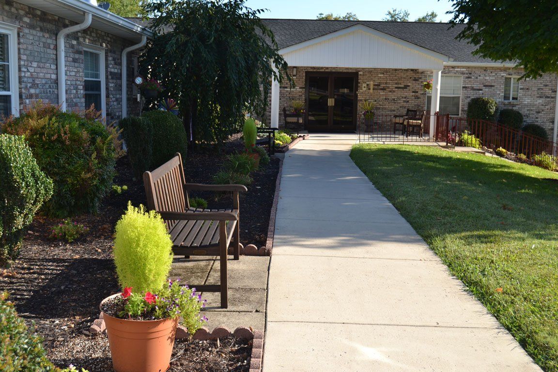 A walkway leading to a house with a bench and potted plants