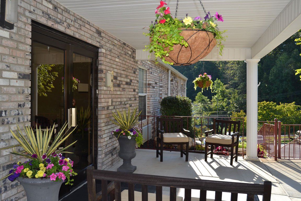 A porch with chairs and a hanging basket of flowers
