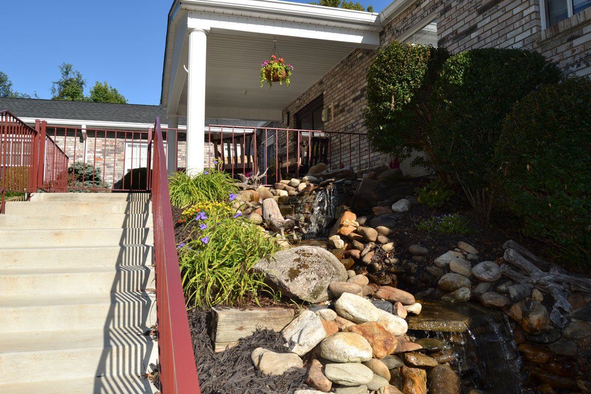 A waterfall is in front of a building with stairs leading up to it.