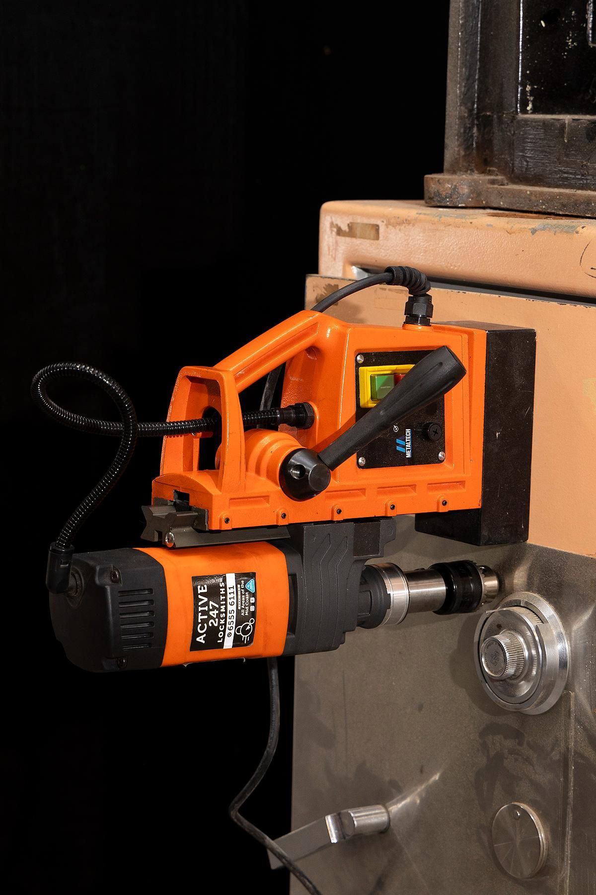 Orange Magnetic Drill Press Attached to a Metal Surface — Active 24/7 Locksmith and Security Services in Forster, NSW