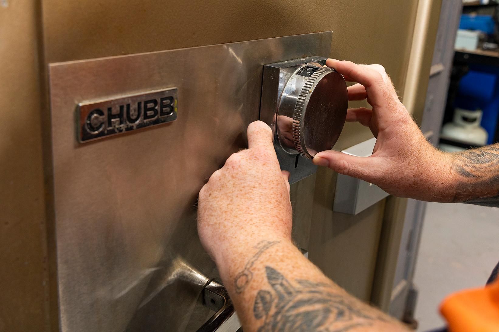 Person's Hands Turning the Dial on a Chubb Safe. The Safe is Metallic, With a Silver Dial — Active 24/7 Locksmith and Security Services in Forster, NSW