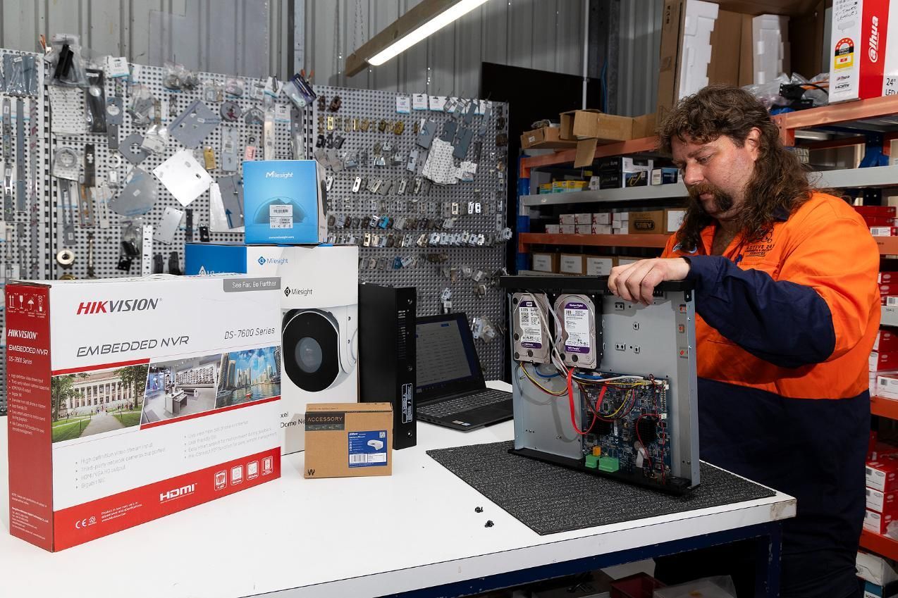 Man With Mullet Assembles a Computer. Boxes and Parts on a Table in a Warehouse — Active 24/7 Locksmith and Security Services in Forster, NSW