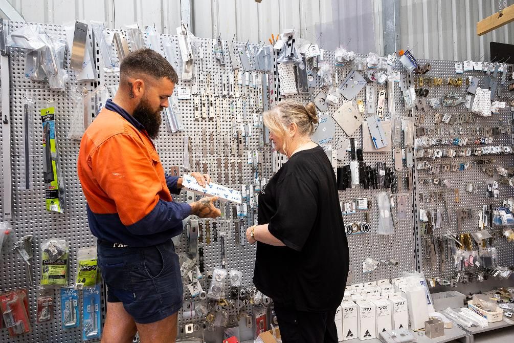 Man in Work Clothes Assists a Woman Selecting Hardware in a Store — Active 24/7 Locksmith and Security Services in Hallidays Point, NSW