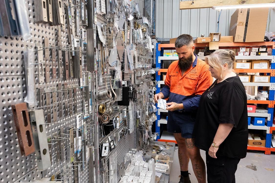 Man and Woman Looking at Keys on a Pegboard Wall in a Workshop — Active 24/7 Locksmith and Security Services in Forster, NSW