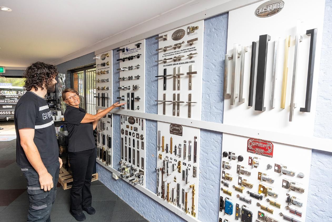 A Woman Points at Door Handles on a Display for a Customer in a Hardware Store — Active 24/7 Locksmith and Security Services in Hallidays Point, NSW