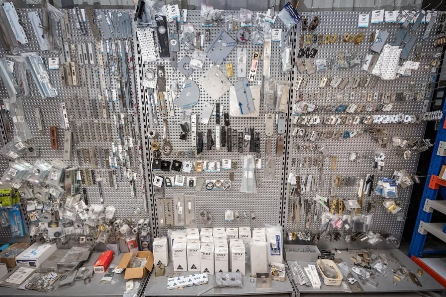 Hardware store display with various metal parts and keys on a pegboard, shelves in the foreground.