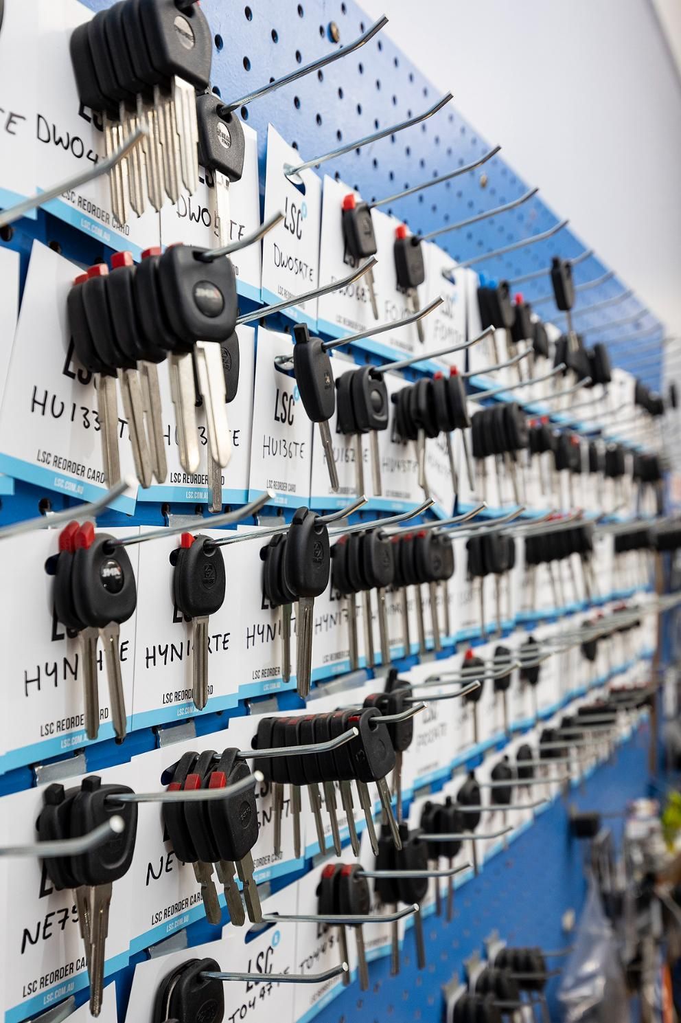 A Display of Car Keys on a Pegboard, Organized With White Labels Against a Blue Background — Active 24/7 Locksmith and Security Services in Forster, NSW