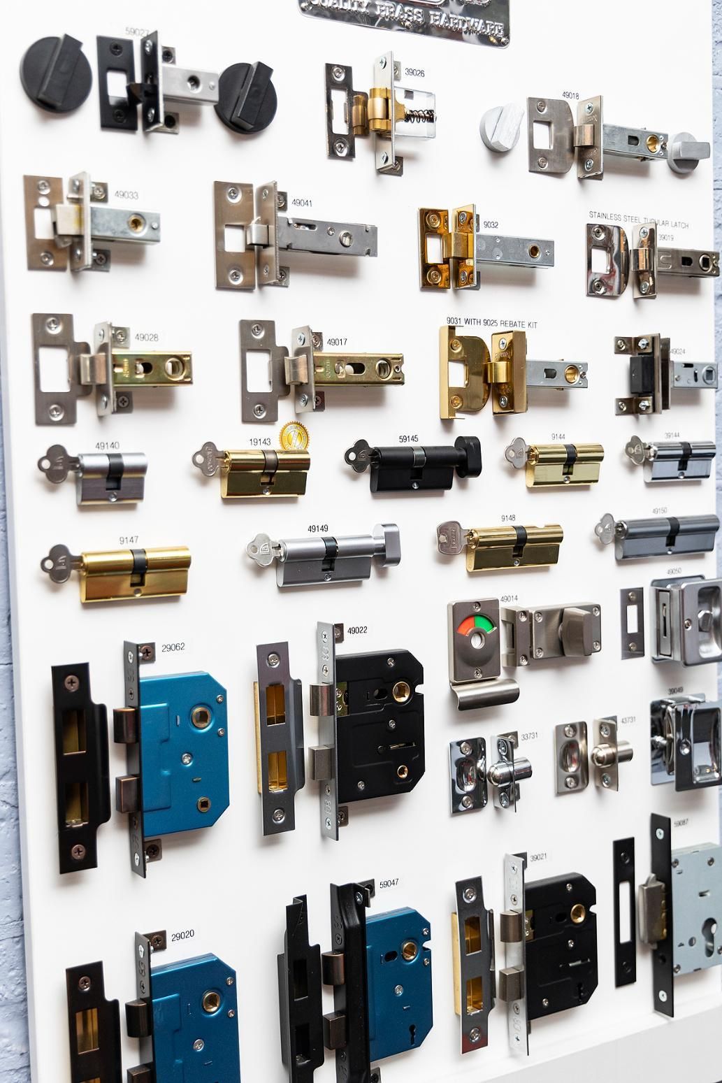 Display of Various Door Latches and Locks in Different Finishes on a White Board — Active 24/7 Locksmith and Security Services in Harrington, NSW