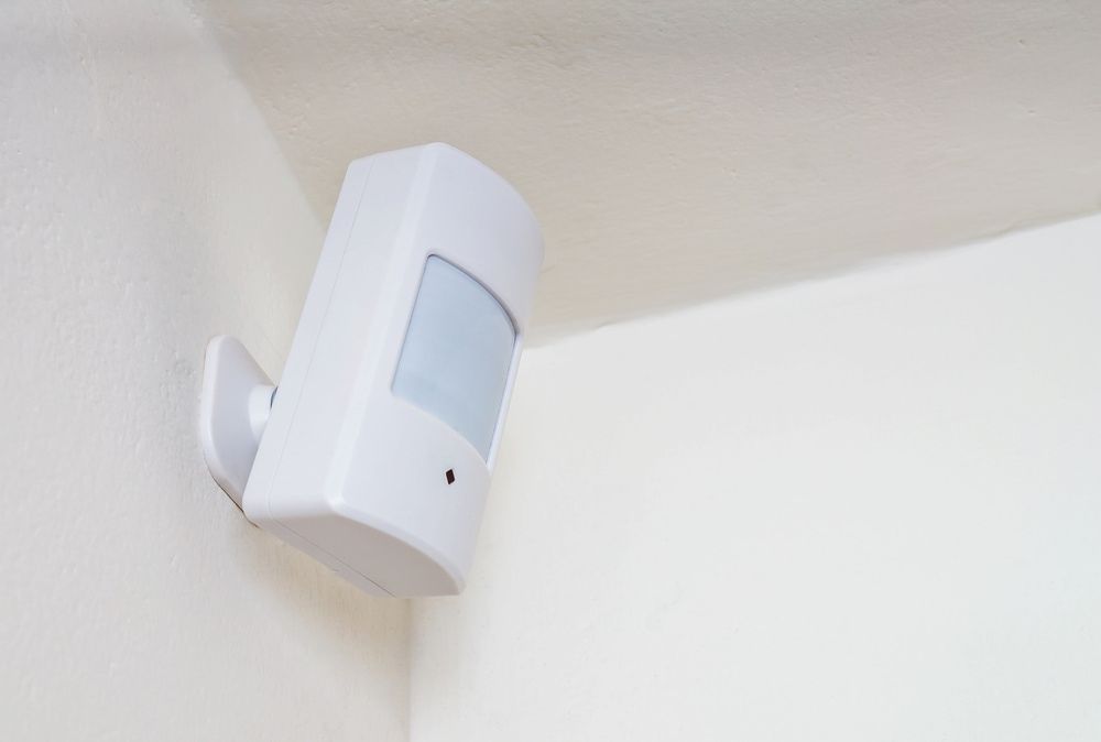 White Motion Sensor Mounted on a White Wall in a Corner — Active 24/7 Locksmiths Forster In Forster, NSW