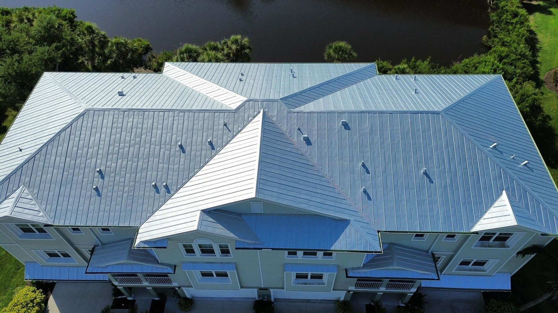 An aerial view of a large white house with a blue roof.