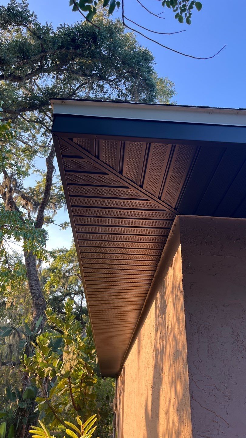 A close up of the roof of a house with trees in the background.