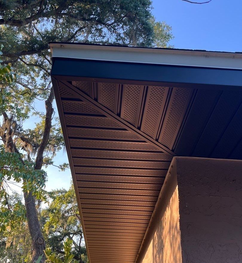 A close up of the roof of a house with trees in the background.