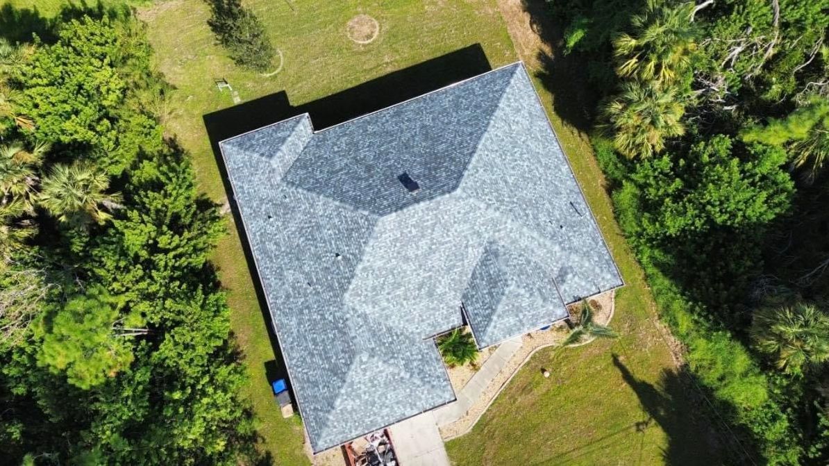An aerial view of a house surrounded by trees and grass.