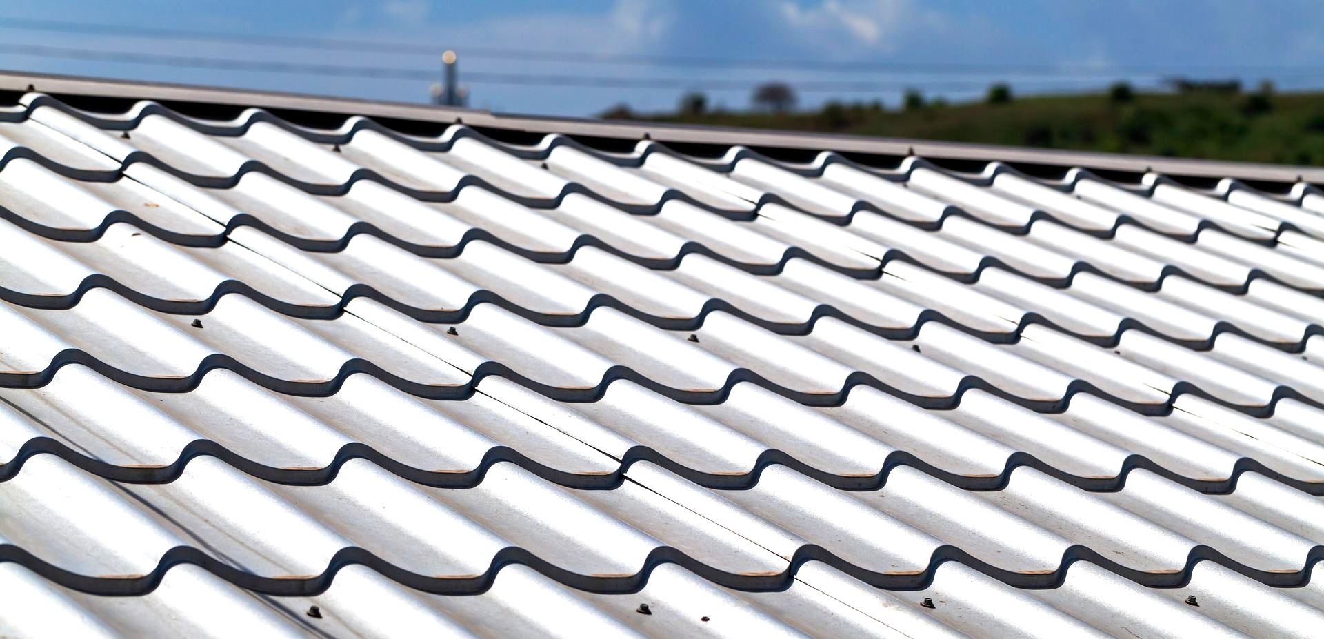 A close up of a white tiled roof with a blue sky in the background.