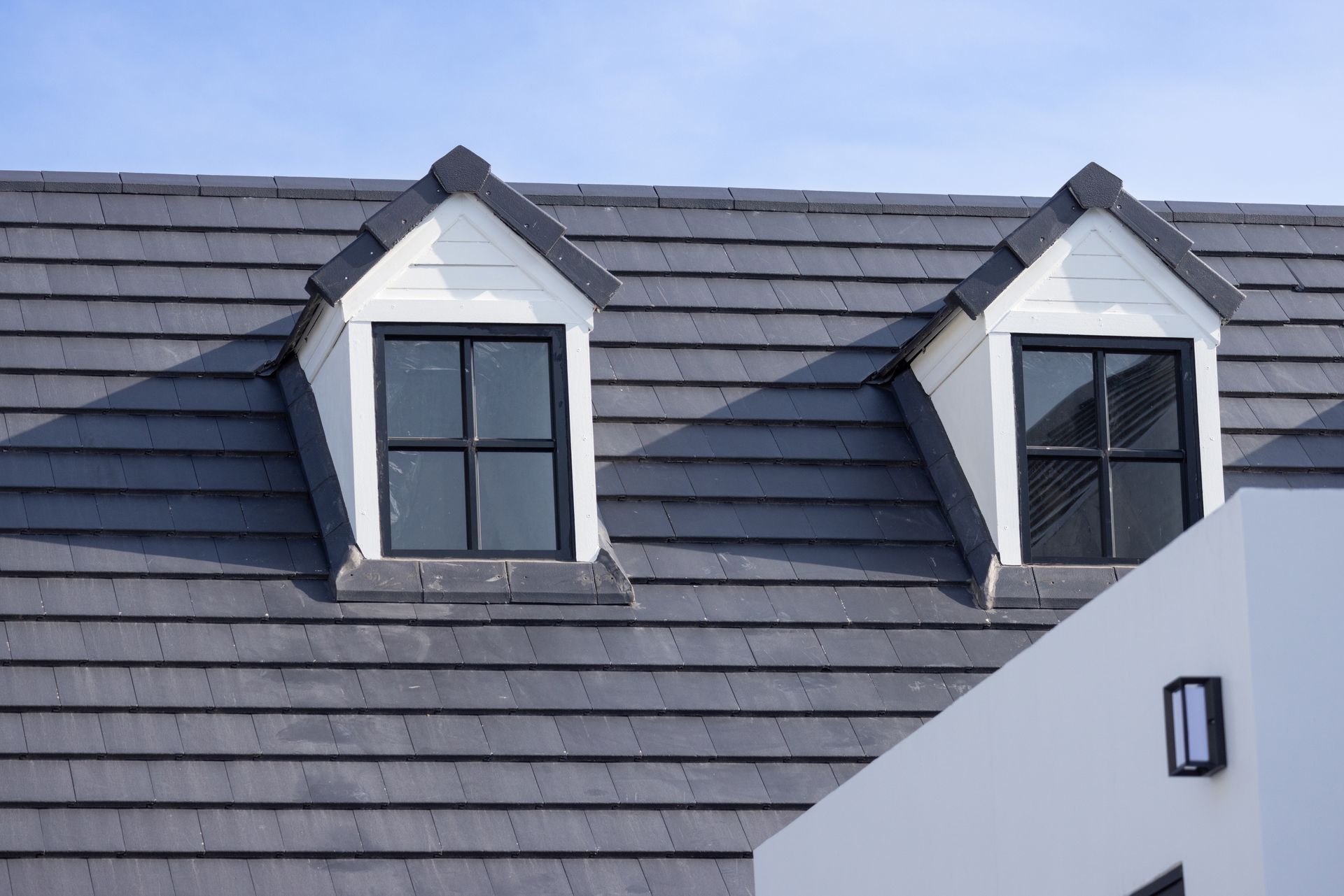 There are two windows on the roof of a house.