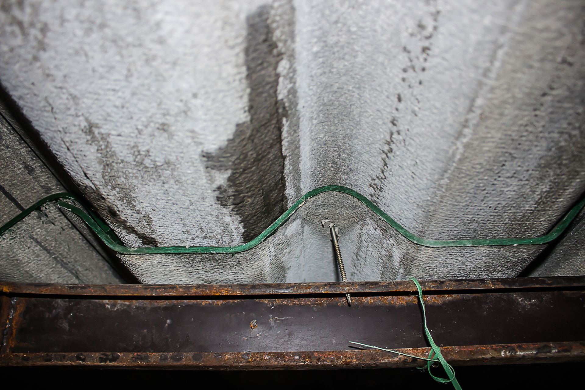 A green wire is hanging from the ceiling of a building.