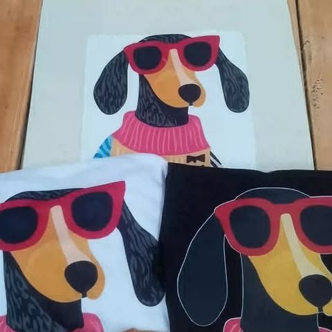 Perro salchicha con gafas de sol rojas y suéter, sobre camisetas blancas, negras y claras.