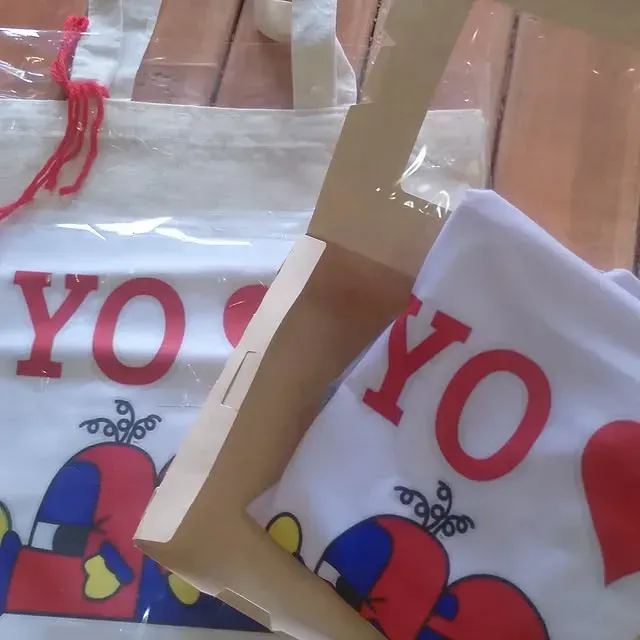 Dos bolsas de mano blancas y una camiseta doblada con la palabra