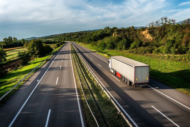 Two semi trucks are driving down a highway.