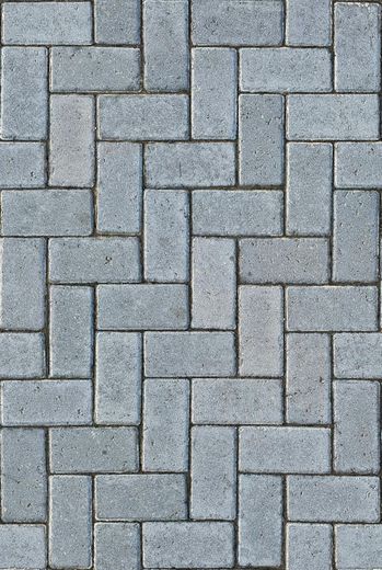 A close up of a brick pavement with a herringbone pattern.