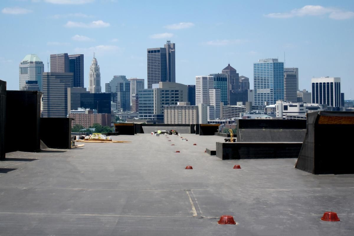 Rooftop with scattered red debris overlooking a city skyline of modern buildings