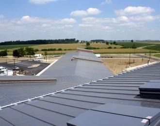 A gray metal roof with a countryside view on a sunny day.