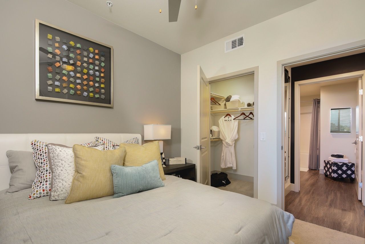 Bedroom with a large bed, decorative pillows, nightstand, and an open closet.