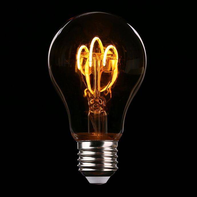 A light bulb is lit up on a black background.