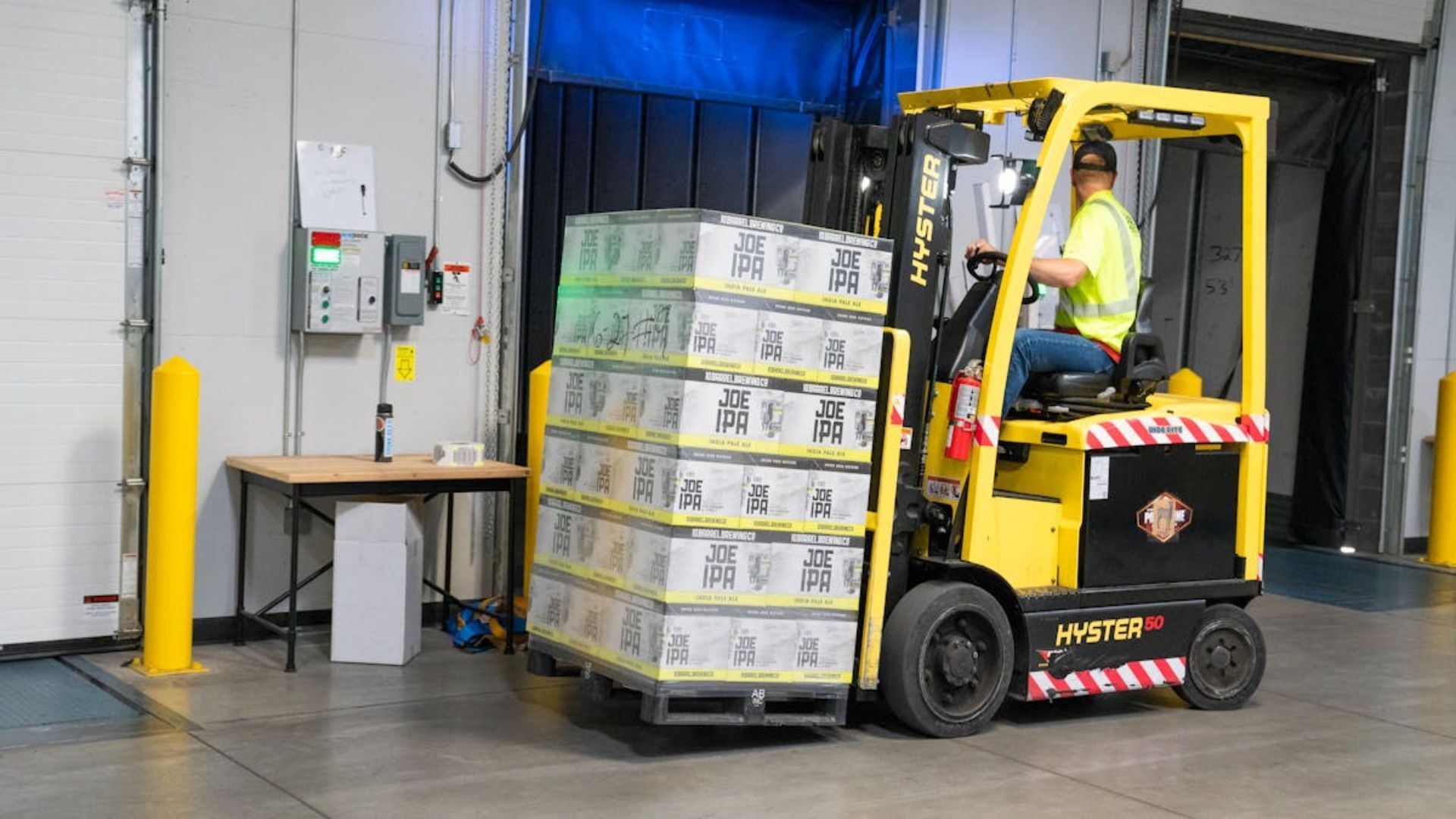 Operador de montacargas en un almacén transportando cajas apiladas sobre un palé.