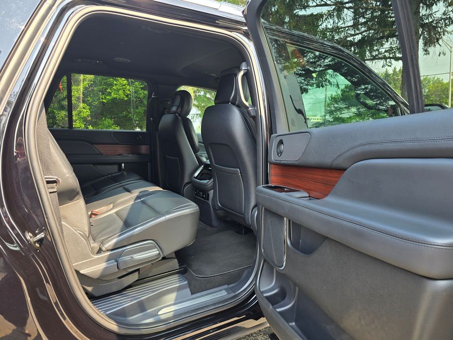 Open black SUV interior with black leather seats, wood trim, and door open.