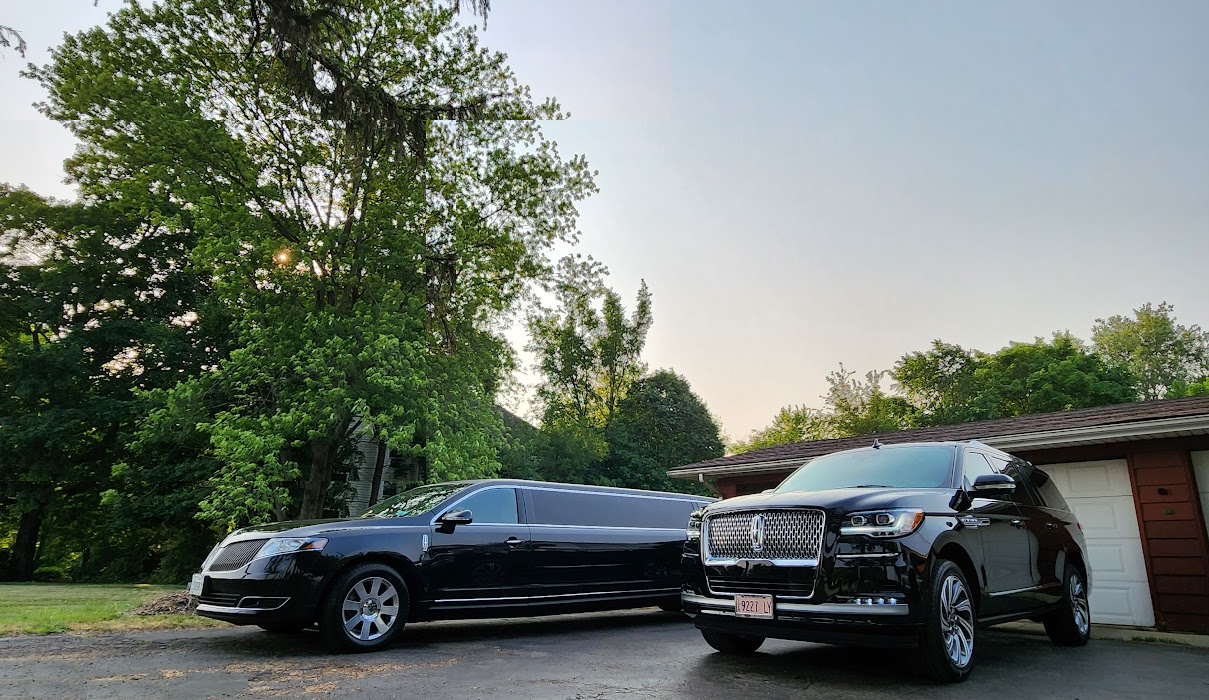 Two black cars are parked next to each other in front of a house.