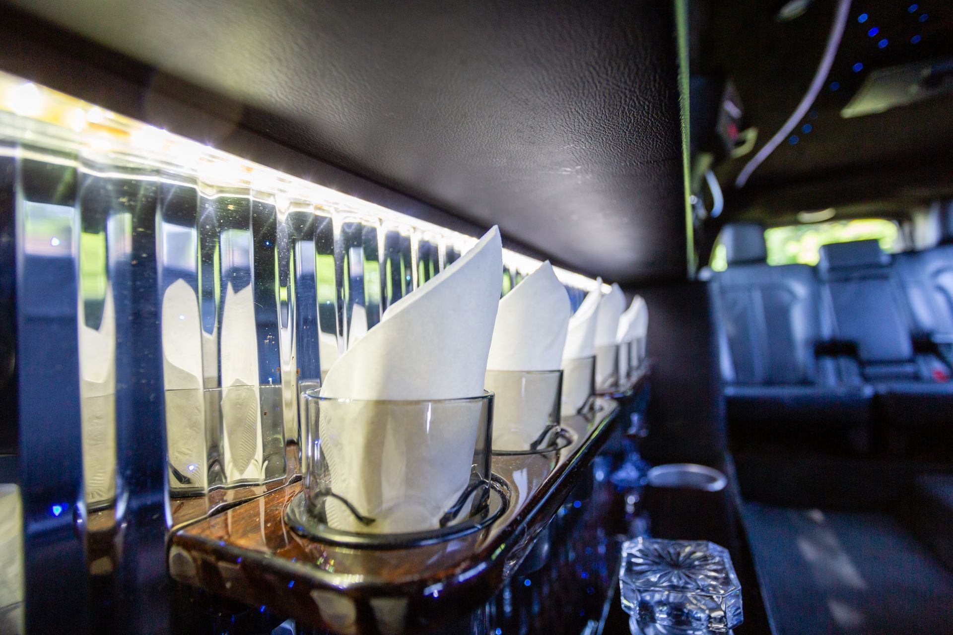 Inside of a limousine with drink holders, napkins, and seating.