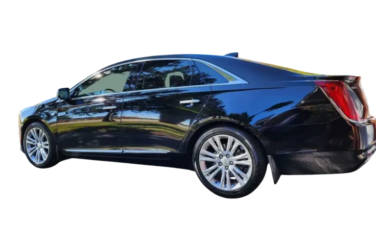 Black Cadillac sedan parked outdoors, shiny, with silver wheels.