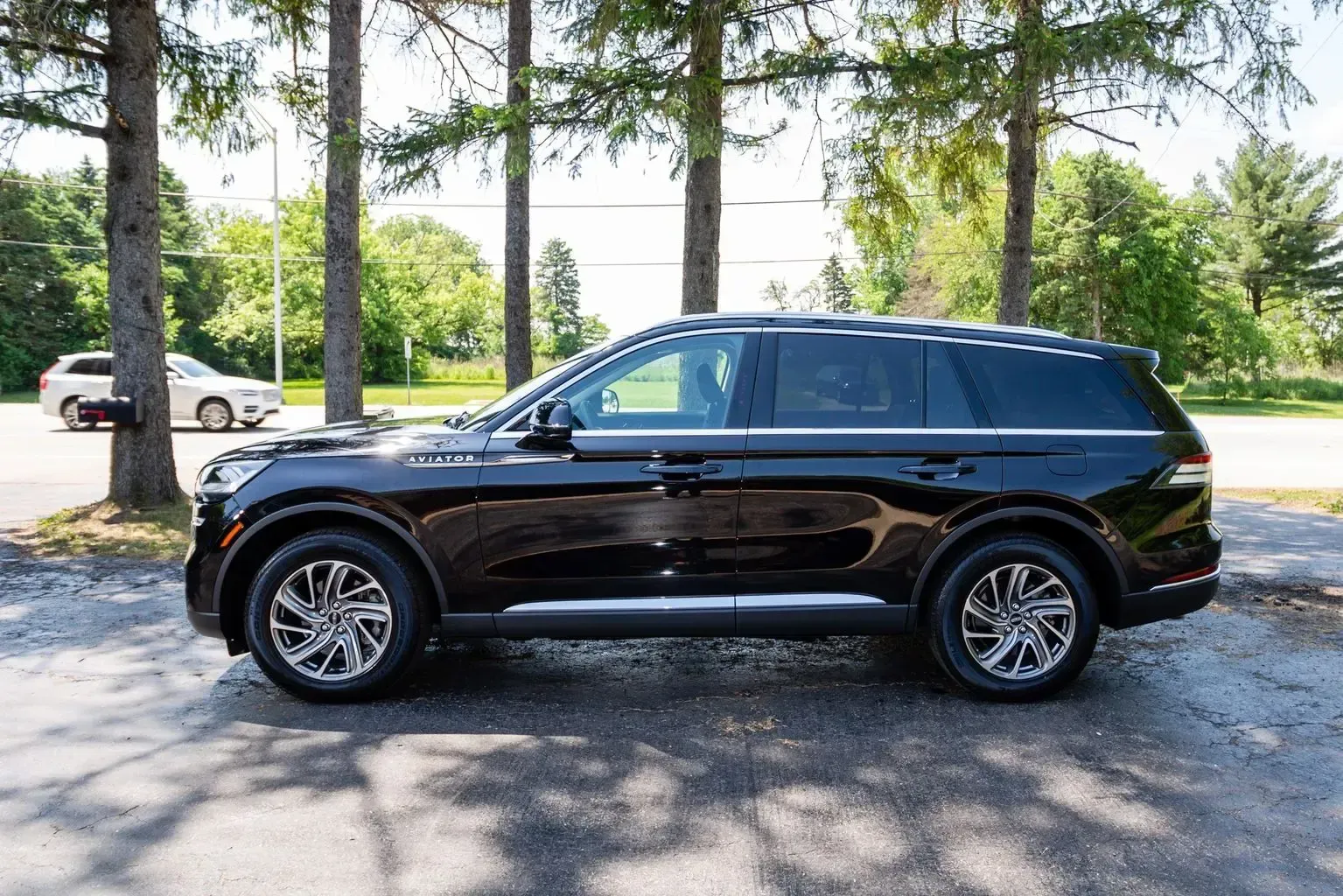 A black suv is parked in a parking lot next to trees.