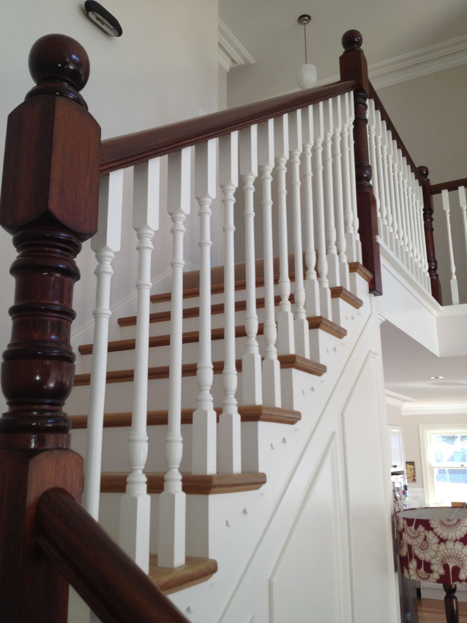 Wooden staircase with white balusters, brown handrail and newel posts.